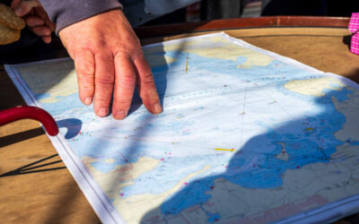 De kapitein wijst het doel aan op de zeekaart