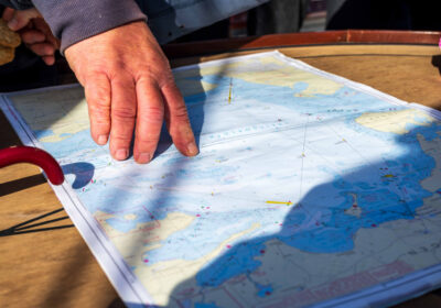 De kapitein wijst het doel aan op de zeekaart