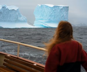 Reizigers aan boord van een expeditieschip tijdens een zeiltocht in de Antarctische wateren