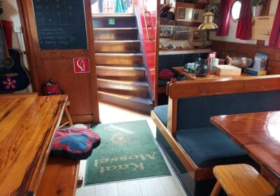 Rustiek dagverblijf met houten tafels en zitbanken aan boord van de Kaat Mossel